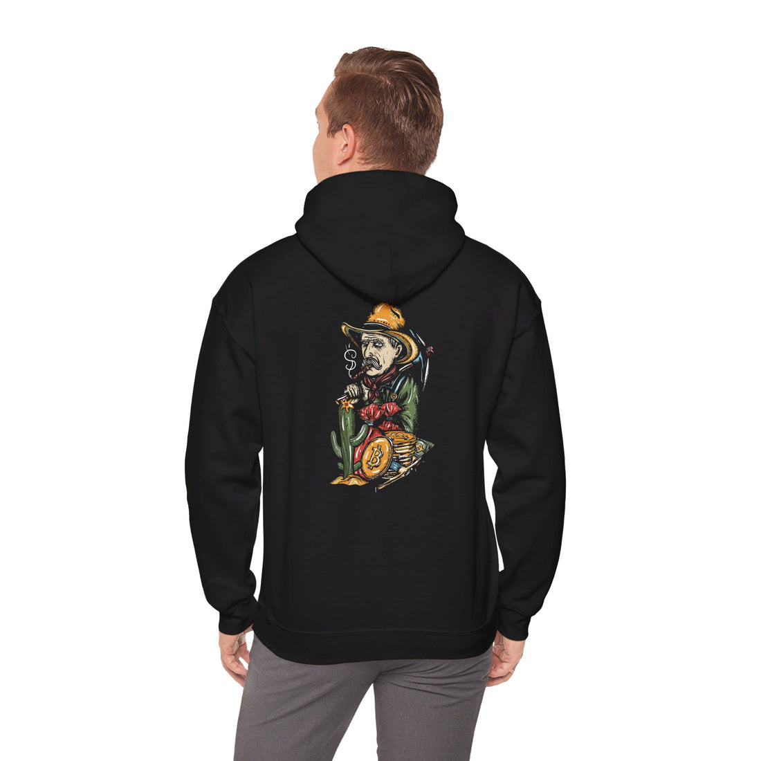 A man stands wearing a black hoodie with a graphic of a skeleton in a cowboy outfit smoking a cigar and holding a bag of money, with a stack of bitcoin coins on the back side of the hoodie.